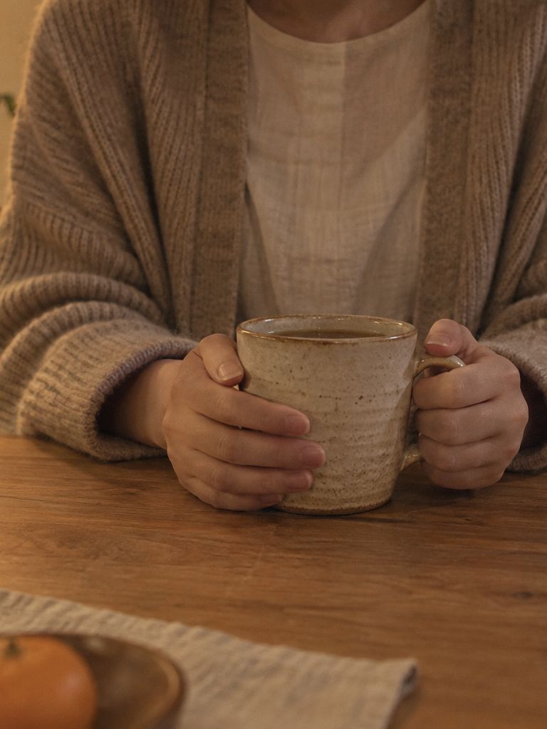 夜の食卓で、お茶を手にする保護者（イメージ）